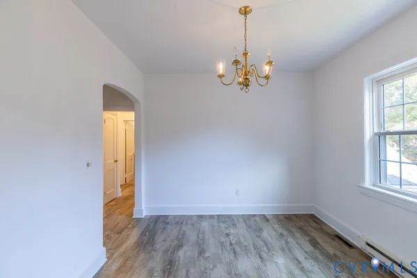 a view of an empty room with window and wooden floor