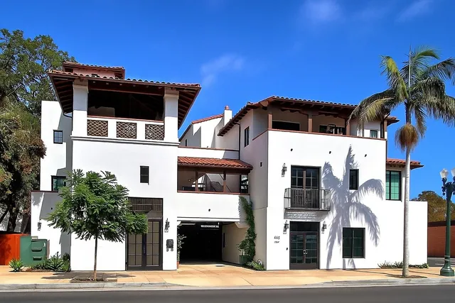 a front view of a building with streets and trees
