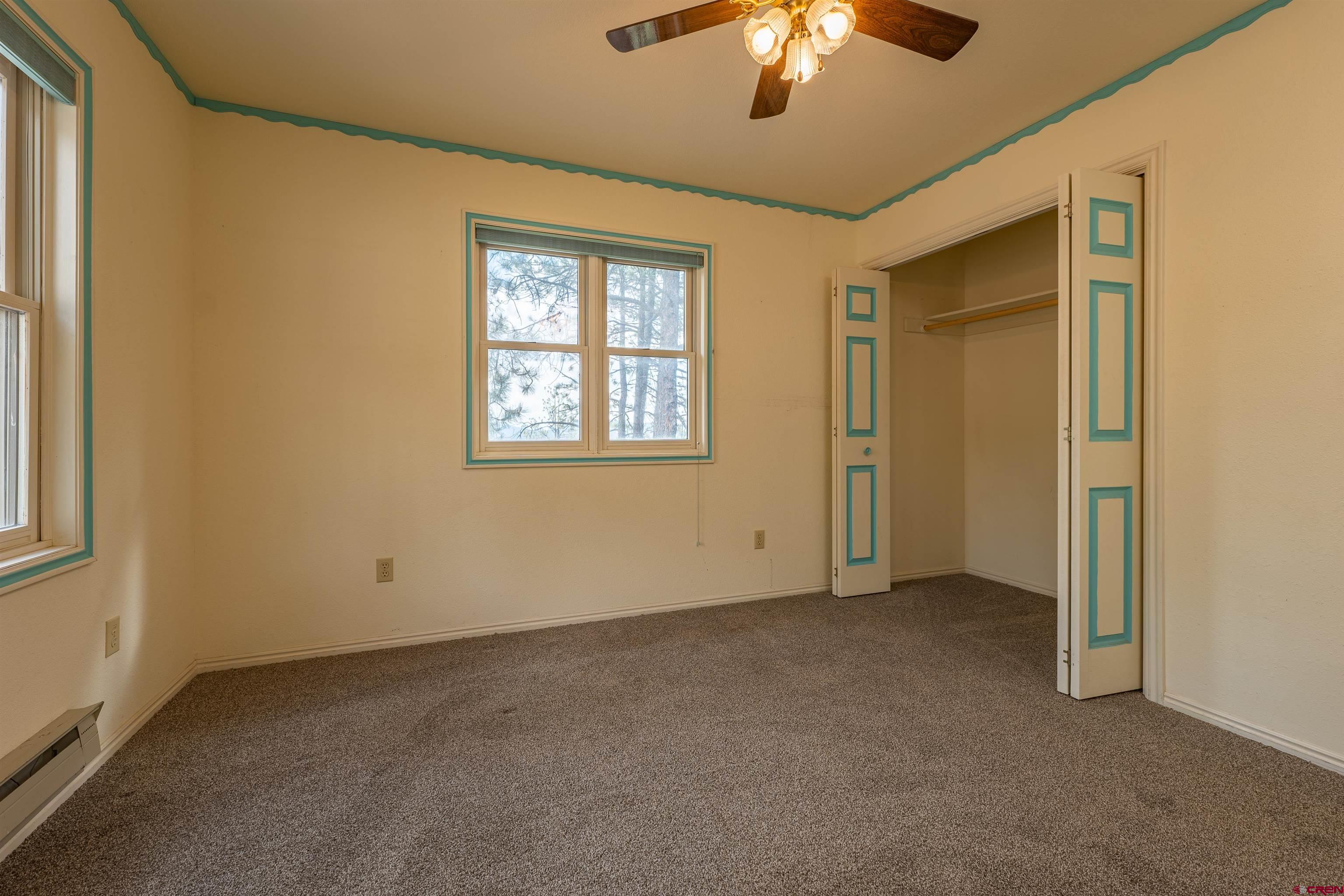 177 Spur Lane Durango, CO 81301 - Photo 18 of 34 an empty room with a chandelier fan and windows