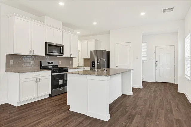a kitchen with granite countertop a sink stove and cabinets
