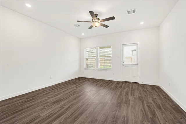 an empty room with windows and ceiling fan view