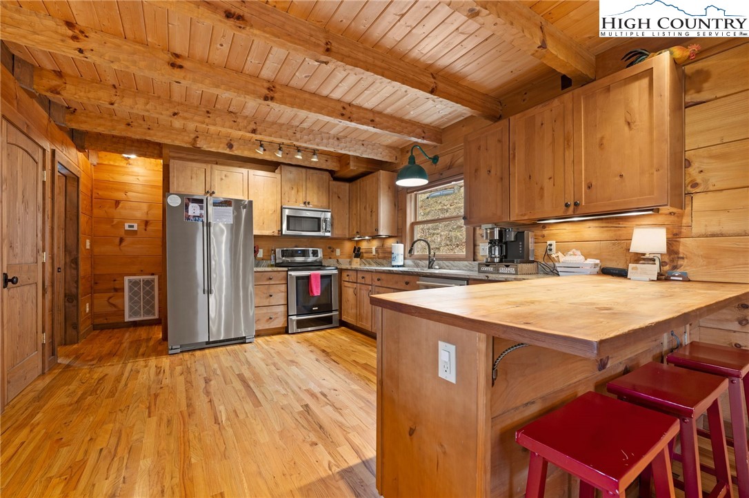 337 Rivers Crest Road Boone, NC 28607 - Photo 11 of 45 a kitchen with stainless steel appliances kitchen island granite countertop a table chairs in it and wooden floors