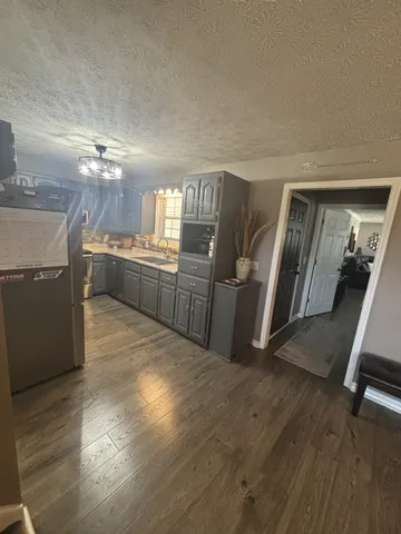 a kitchen with granite countertop a refrigerator stove and wooden floor