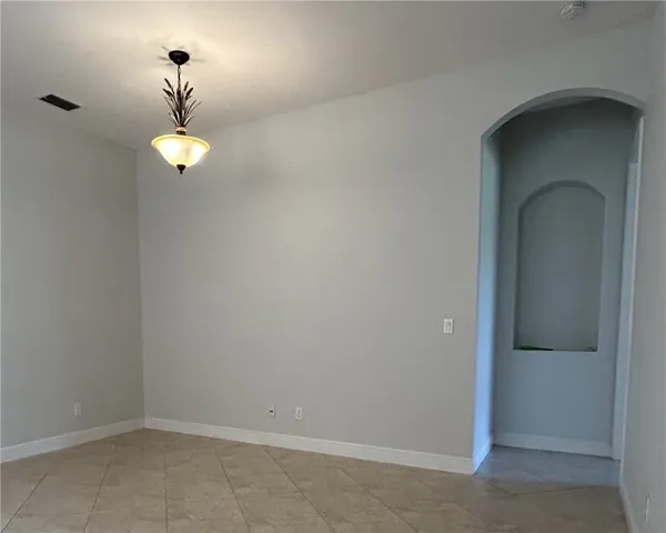 a open kitchen with granite countertop a stove and a refrigerator with white cabinets