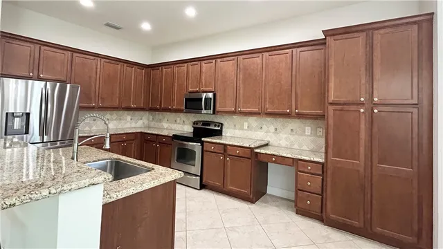 a kitchen with kitchen island granite countertop a sink stove and refrigerator