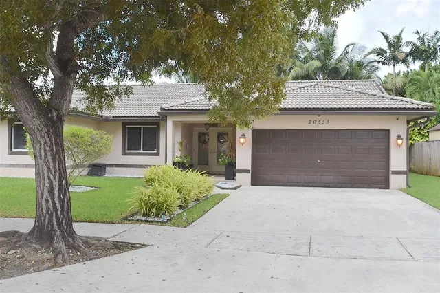 a front view of a house with a garden and trees