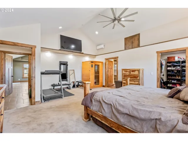 a bedroom with a bed a table and chair with the large mirror
