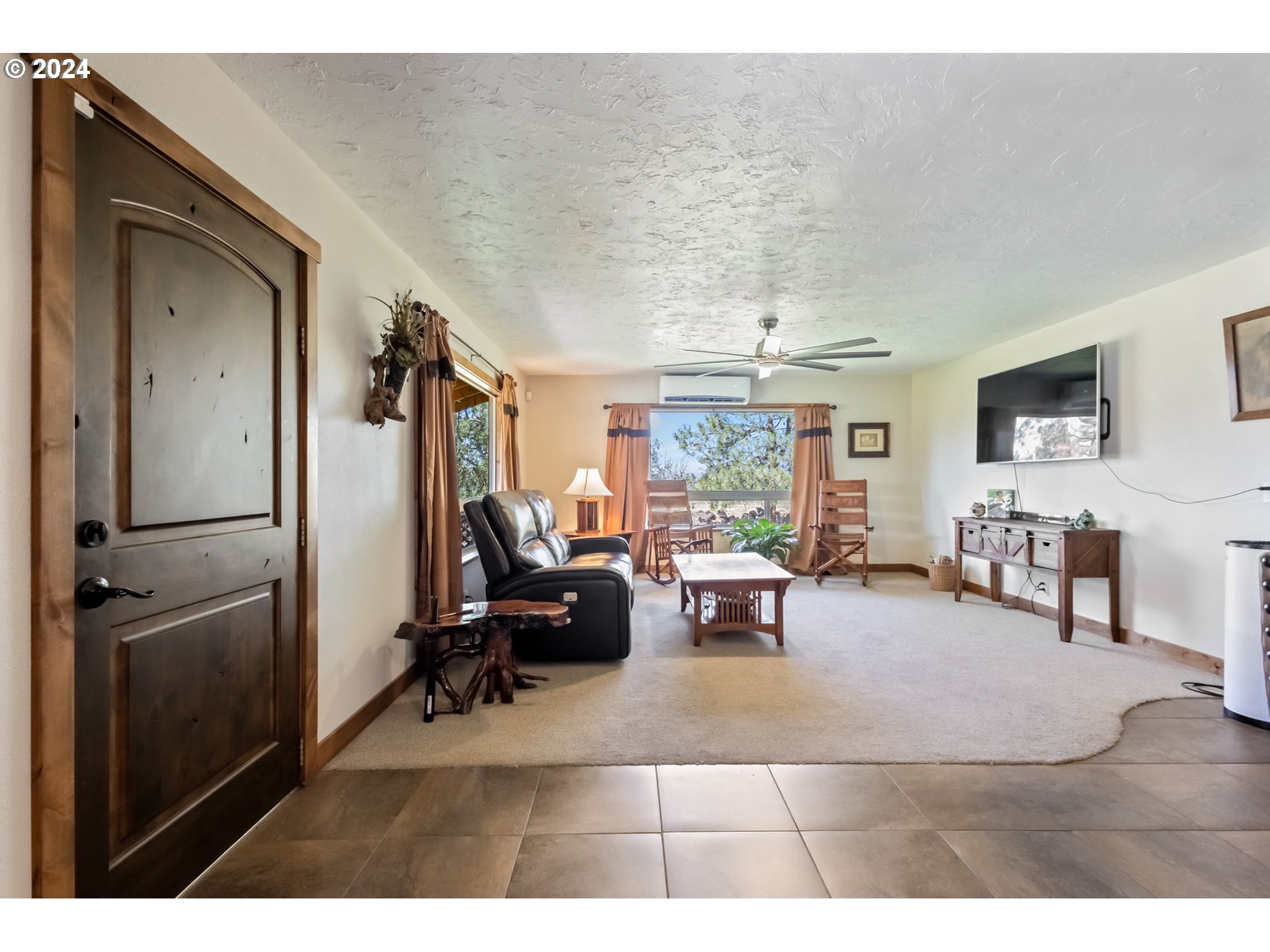 3068 Southwest Reif Road Powell Butte, OR 97753 - Photo 3 of 42 a living room with furniture a large window and a flat screen tv