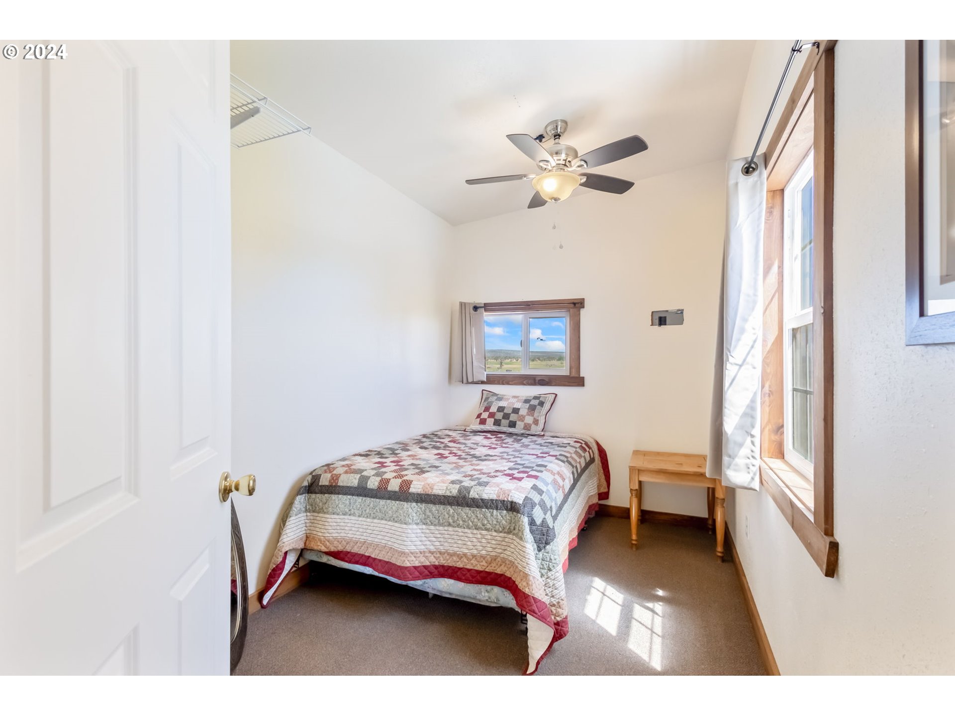 3068 Southwest Reif Road Powell Butte, OR 97753 - Photo 33 of 42 a bedroom with a bed chandelier and a window