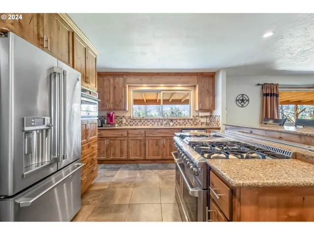 a kitchen with stainless steel appliances granite countertop a stove a sink and a refrigerator