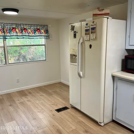 a view of a refrigerator in kitchen and an empty room