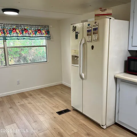 a view of a refrigerator in kitchen and an empty room