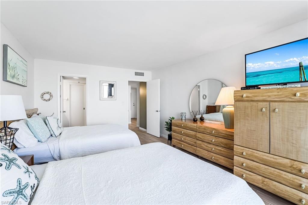 5 Bluebill Avenue, Unit 810 Naples, FL 34108 - Photo 11 of 19 a bedroom with a bed and wooden floor