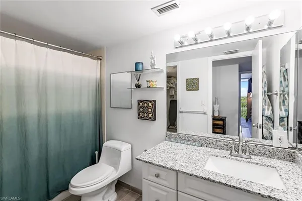 a bathroom with a granite countertop sink mirror vanity and toilet