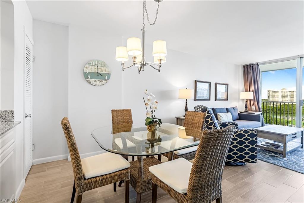5 Bluebill Avenue, Unit 810 Naples, FL 34108 - Photo 8 of 19 a dining room with furniture a rug and a chandelier