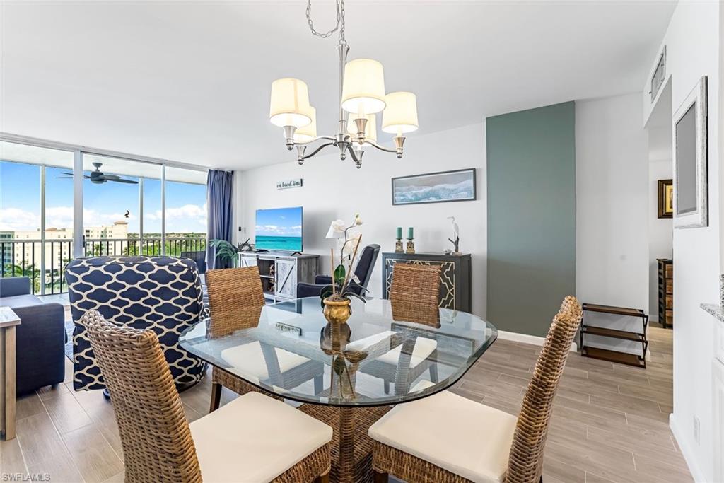 5 Bluebill Avenue, Unit 810 Naples, FL 34108 - Photo 9 of 19 a view of a dining room with furniture a chandelier and wooden floor