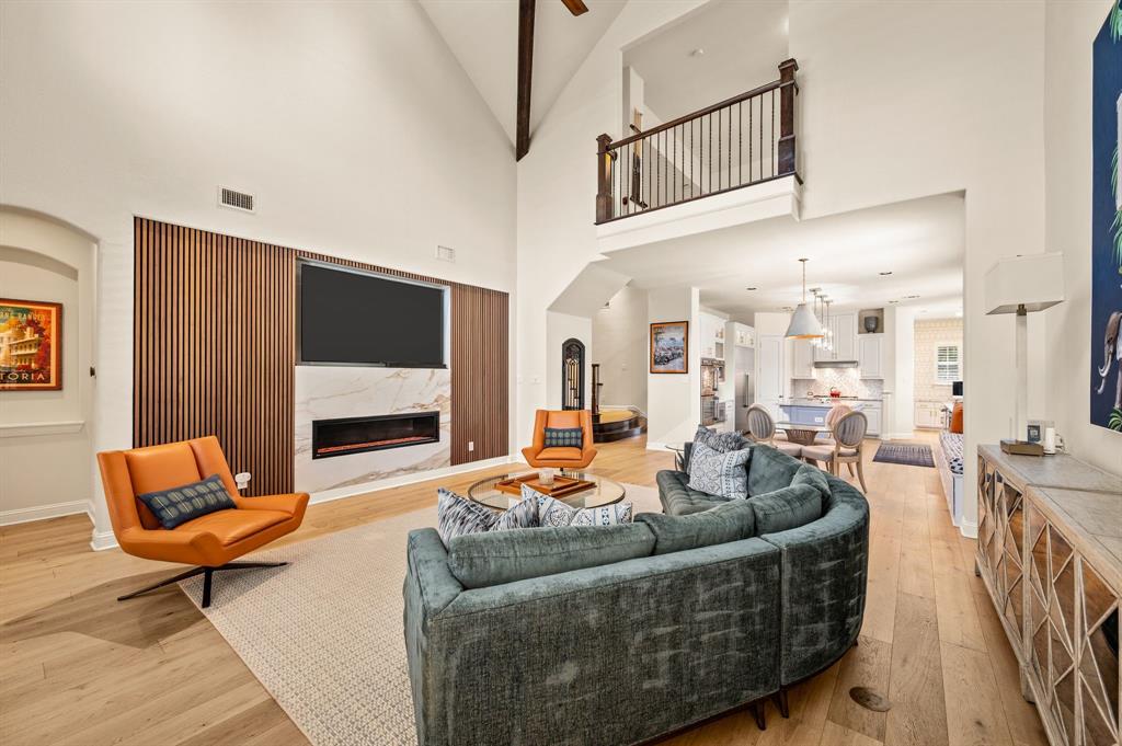 1521 Newton Ranch Road Keller, TX 76248 - Photo 10 of 40 Vaulted ceilings with exposed beams, wood flooring, a built-in fireplace with a stone surround, and an open loft area with a wrought iron railing