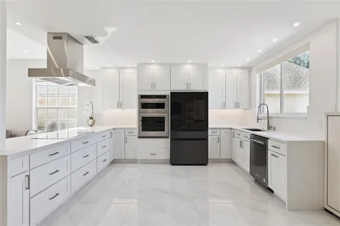 a large white kitchen with stainless steel appliances