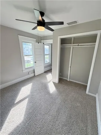 a view of empty room with wooden floor and fan