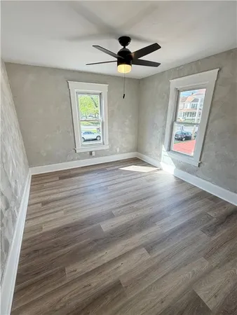 a view of an empty room with wooden floor and a window