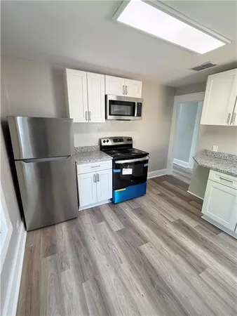a kitchen with granite countertop a refrigerator and a stove top oven