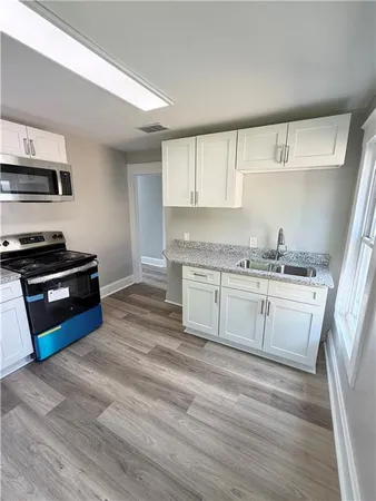 a kitchen with stainless steel appliances a stove a sink and white cabinets