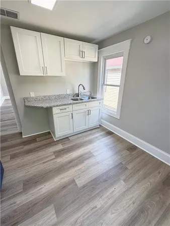 a kitchen with granite countertop white cabinets a sink a window and stainless steel appliances
