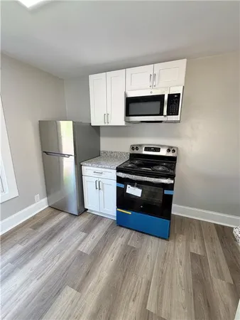 a kitchen with stainless steel appliances a stove a microwave and white cabinets