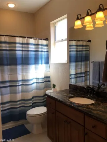 a bathroom with a granite countertop sink and a toilet