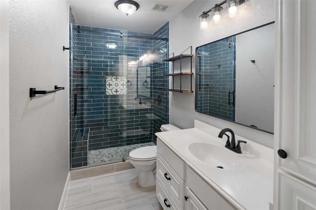 1019 Vaughan Lane Tioga, TX 76271 - Photo 11 of 40 Bathroom featuring a glass-enclosed shower with dark teal subway tile, a decorative accent tile, and a pebble-style shower floor