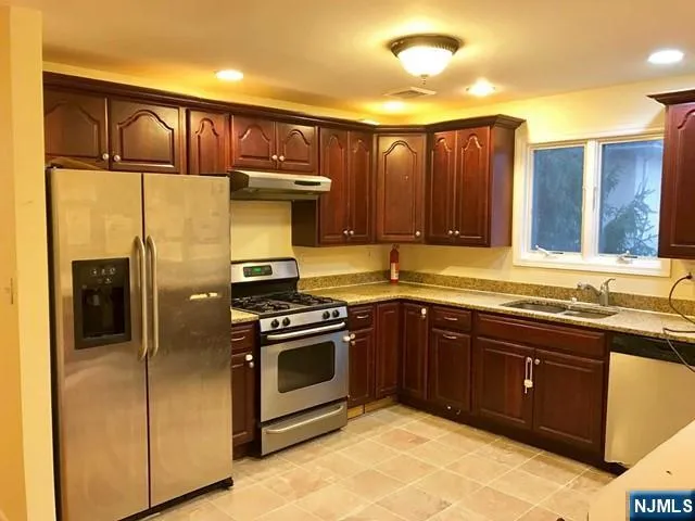 a kitchen with stainless steel appliances granite countertop a stove a sink and a refrigerator