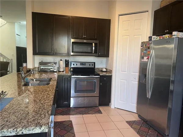 a kitchen with stainless steel appliances granite countertop a refrigerator stove top oven dining table and chairs