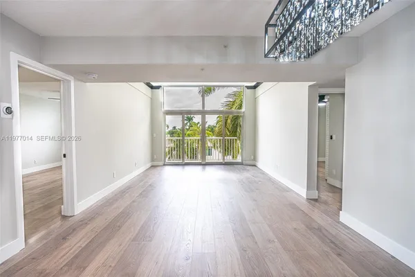 a view of an empty room with wooden floor and a window