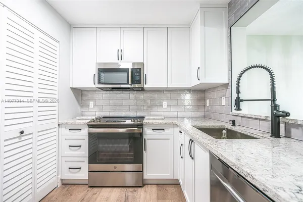 a kitchen with granite countertop white cabinets and appliances