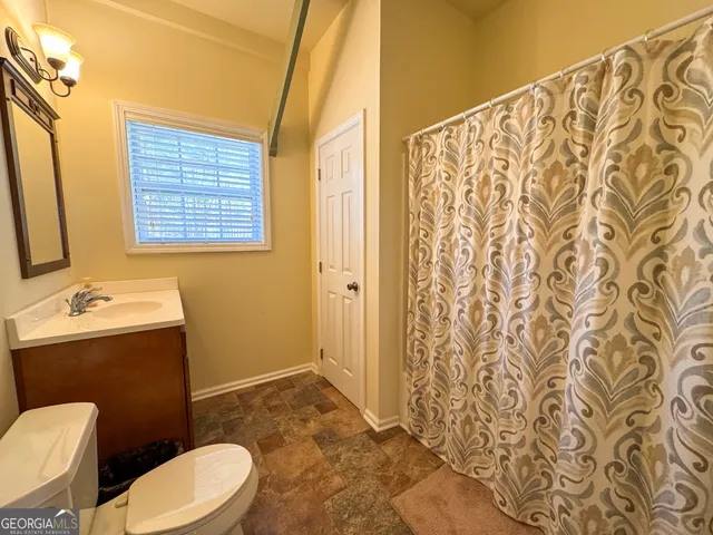 a bathroom with a sink a toilet and shower curtain