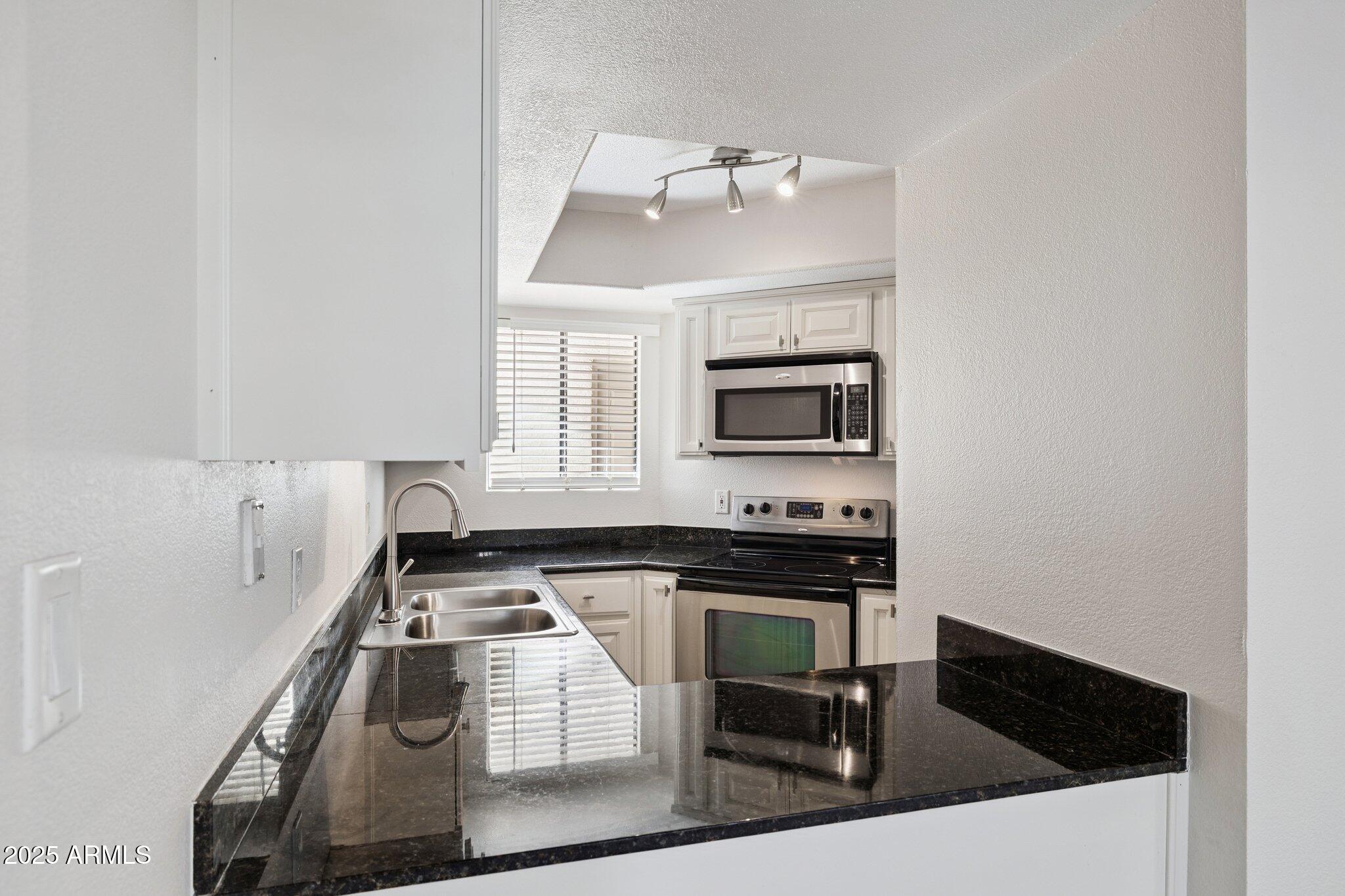 935 North Granite Reef Road, Unit 100 Scottsdale, AZ 85257 - Photo 8 of 35 a kitchen with a sink a stove and cabinets