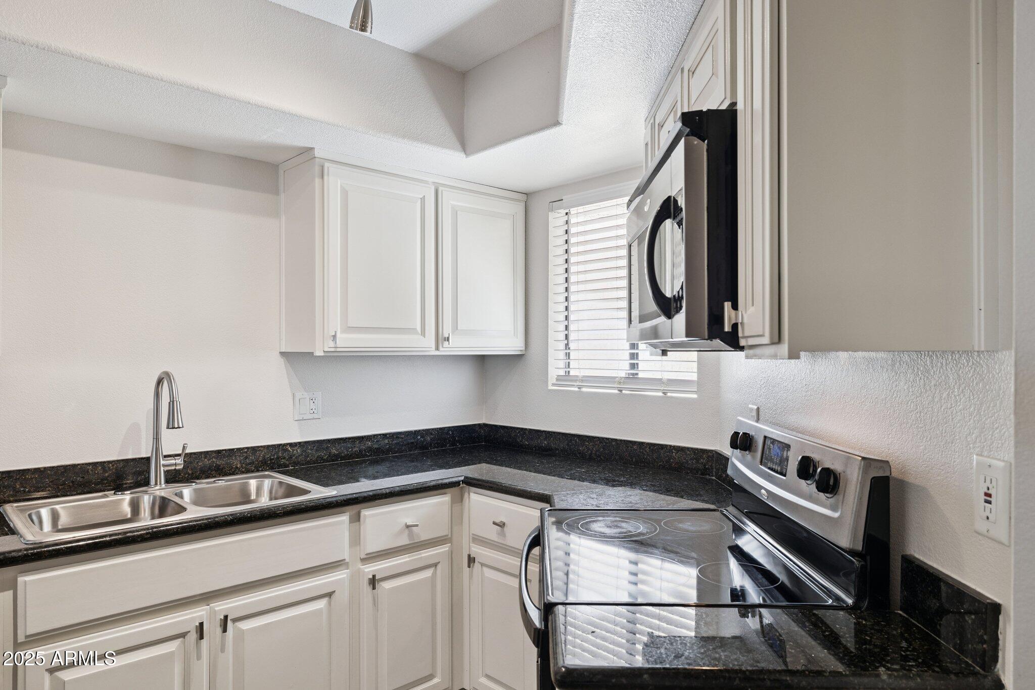 935 North Granite Reef Road, Unit 100 Scottsdale, AZ 85257 - Photo 9 of 35 a kitchen with granite countertop a sink stainless steel appliances and cabinets