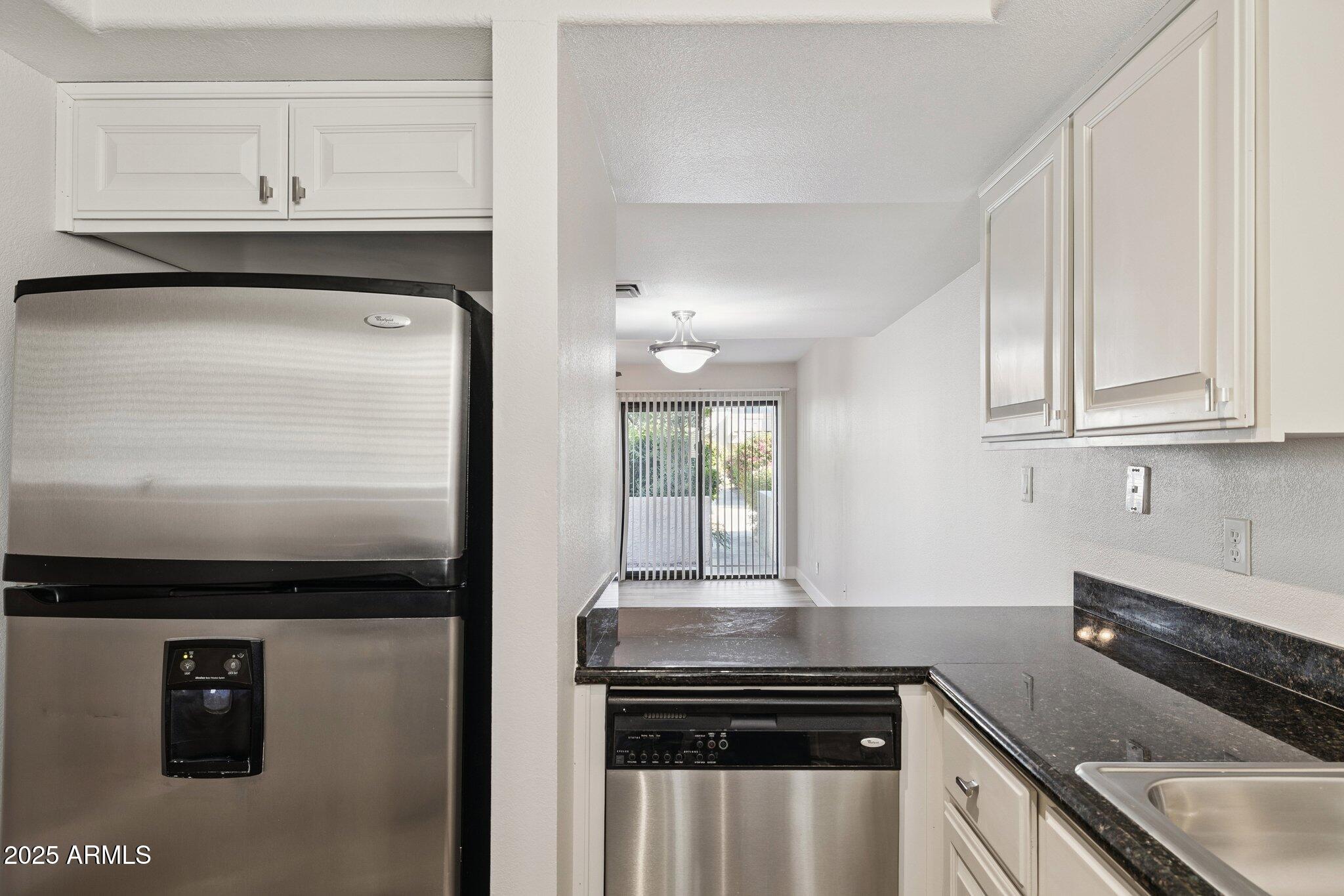935 North Granite Reef Road, Unit 100 Scottsdale, AZ 85257 - Photo 10 of 35 a kitchen with granite countertop white cabinets and stainless steel appliances