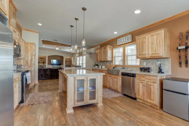 a large kitchen with stainless steel appliances granite countertop a stove a sink dishwasher and a oven with white cabinets