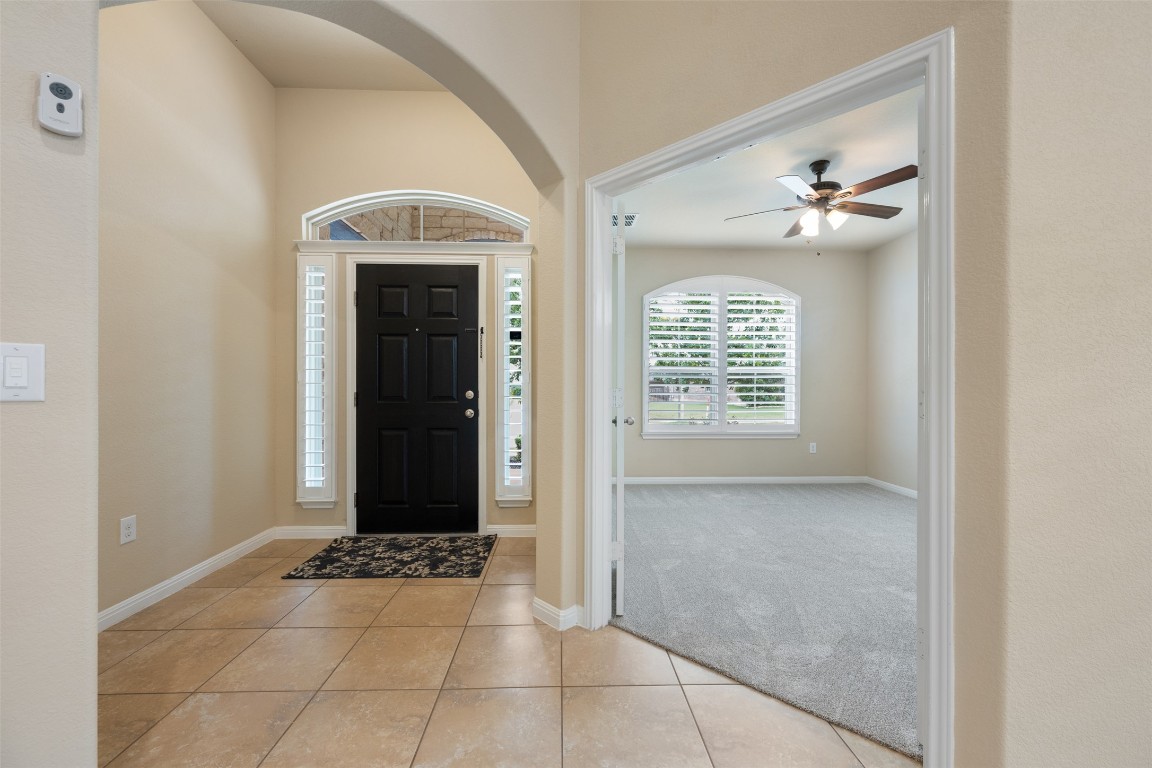 533 Flag Lane Leander, TX 78641 - Photo 2 of 40 Foyer entrance with arched walkways, with entrance to 1st floor office/flex room with ceiling fan and natural light-plantation shutters and newly installed carpet