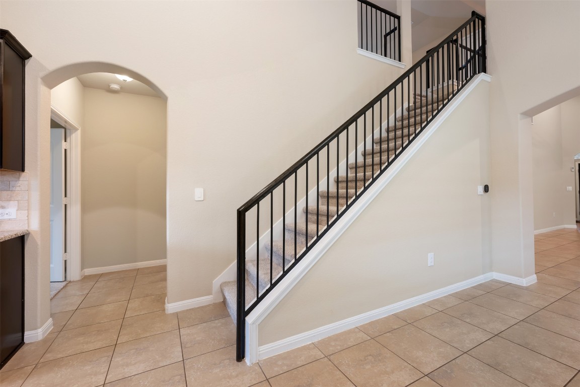 533 Flag Lane Leander, TX 78641 - Photo 24 of 40 Staircase with tile patterned floors, arched walkways, a high ceiling, and baseboards