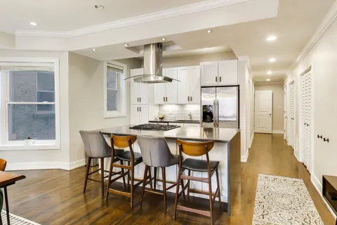 a dining hall with stainless steel appliances kitchen island granite countertop wooden floor a dining table and chairs