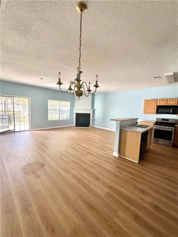a view of a room with kitchen island stainless steel appliances wooden floor and living room view