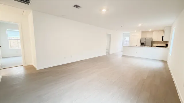 a view of a kitchen with kitchen island a sink wooden floor and a refrigerator