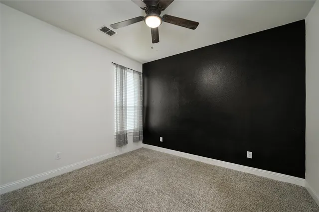 an empty room with ceiling fan and window