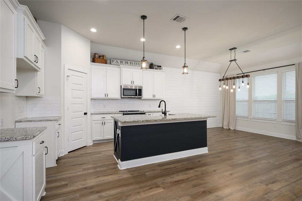 300 Bronco Drive Pilot Point, TX 76258 - Photo 8 of 31 a large kitchen with stainless steel appliances a stove a sink dishwasher a refrigerator and white cabinets with wooden floor