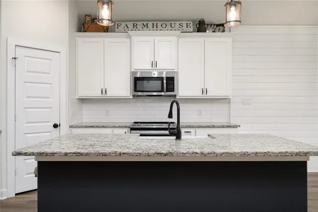 a kitchen with granite countertop a sink stainless steel appliances and cabinets