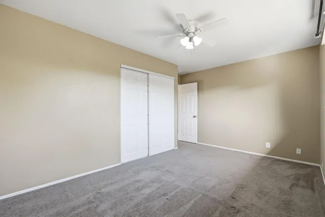 an empty room with a chandelier fan and windows