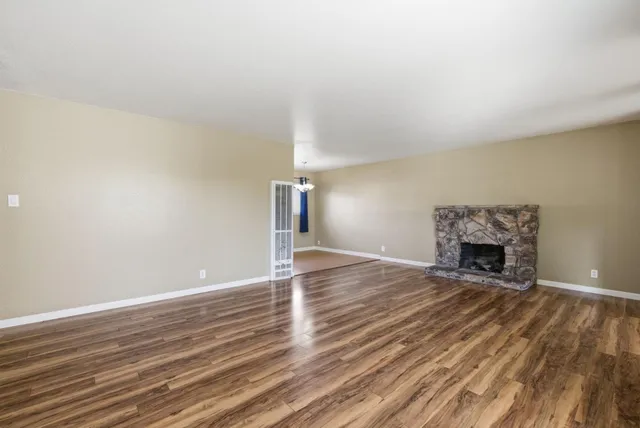 a view of empty room with wooden floor and fireplace