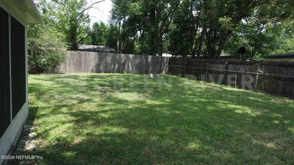 a view of a backyard with a garden and wooden fence